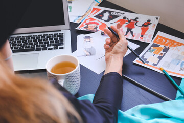 Female fashion designer with laptop working in studio, closeup