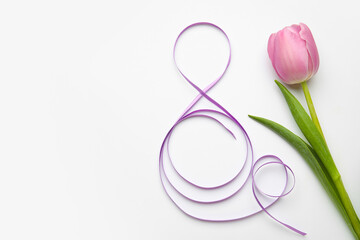 Figure 8 made of violet ribbon and tulip flower on light background. International Women's Day...