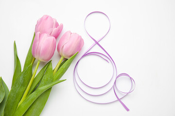Obraz na płótnie Canvas Figure 8 made of violet ribbon and tulip flowers on light background. International Women's Day celebration