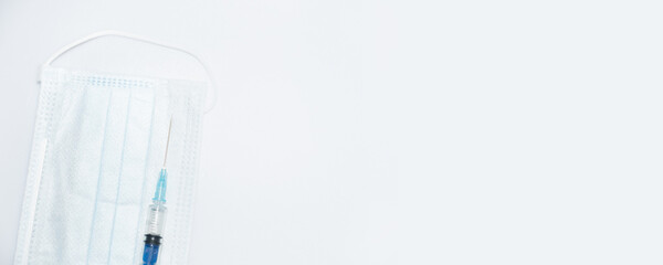 One single syringe with dose of medicine or vaccine with one single protective face mask on white...