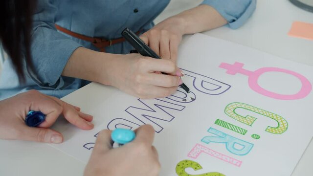 Close-up of female hands drawing colorful girl power banners fighting for gender equality and women empowerment. Feminism and freedom concept.
