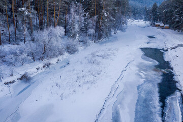 View of almost frozen Sema river and tourist camping on its bank. Kamlak village, Altai Republic, Russia.