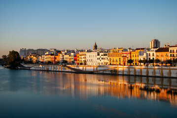 the Triana neighborhood reflected on the Guadalquivir River in Seville, Spain - obrazy, fototapety, plakaty