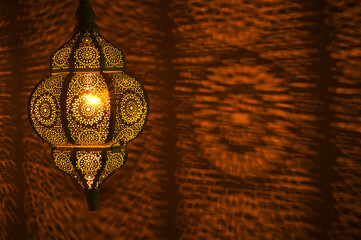 Moroccan golden lamp with circular patterns of light on wall in horizontal position.