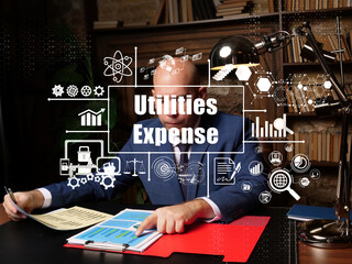 Business concept about Utilities Expense with sign. Serious young businessman looking report in office on background.