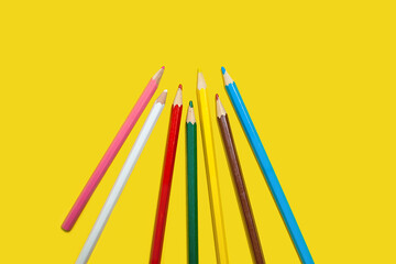 set of colored pencils on a yellow background