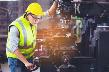 Professional engineer metalworker operating machine center in manufacturing workshop, check...