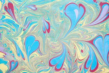 An illustration in the art of an ebru with multicolored hearts of liquid acrylic paint spreading over paper. Bright pastel colors