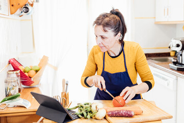 Obraz na płótnie Canvas woman cooking using tablet to follow the recipe