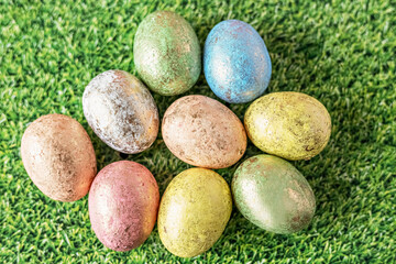 Easter eggs in pastel colors on a green background with grass texture. View from above