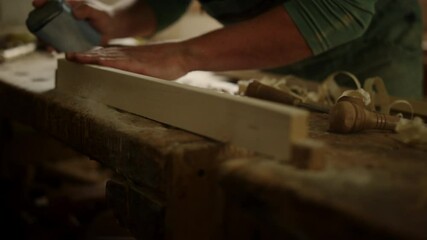 Man checking wood softness in studio. Unknown guy using sandpaper in carpentry 