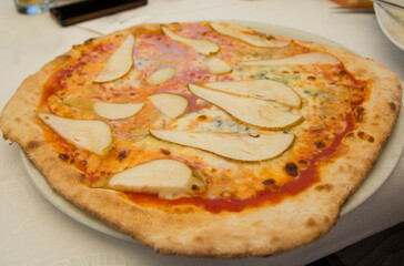 Big Italian pizza with fresh pears, tomato sauce and Gorgonzola blue cheese