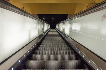 Rolltreppe mit Blick nach unten, die Seiten sind beleuchtet. Ungewöhnlicher Blickwinkel