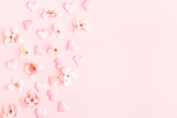 Obraz na płótnie Canvas Valentine's Day background. Pink flowers, hearts on pastel pink background. Valentines day concept. Flat lay, top view, copy space