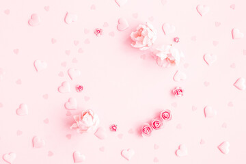 Valentine's Day background. Frame made of pink flowers, hearts on pastel pink background....