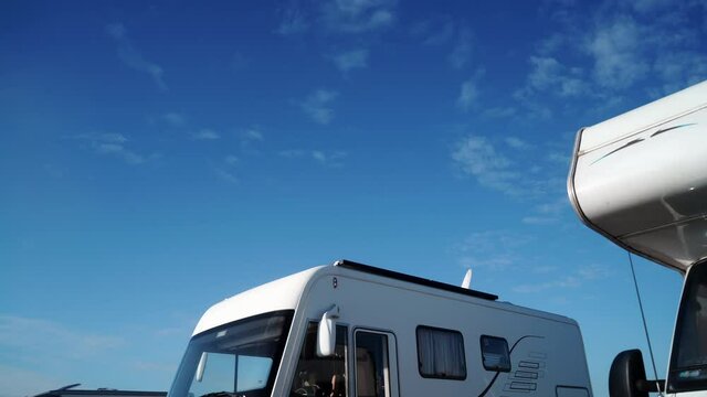 Camper vehicles outdoors on nature and clouds moving across blue sky. Time lapse