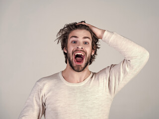 Barber and hairdresser, male fashion. Sleepy man with beard on grey background. Uncombed hair. Man with disheveled hair in underwear. Morning wake up, everyday life