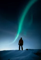 Kussenhoes Een persoon die in de winter op een besneeuwde rots staat en naar het noorderlicht aan de hemel kijkt © Jamo Images