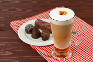 Cup of coffee and saucer with chocolate sweets on wooden table