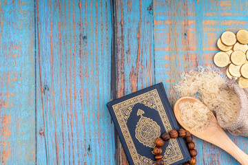Holy Quran with arabic calligraphies translation meaning of Al-Quran, Coins, Rosary and Rice. Zakat concept. Zakat is a form of alm-giving as a religious obligation