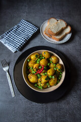 Indian snacks item dum aloo or steamed potatoes and bread slices on a plate. View from top, selective focus.