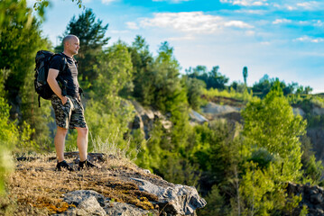 Hiker trekking on the mountains and contemplating the panorama. Man is carrying a backpack and...