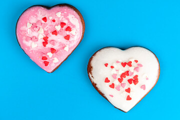 Obraz na płótnie Canvas one pink and one white heart-shaped gingerbreads on blue background