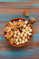 a wooden bowl with walnuts and hazelnuts on blue and brown wood boards
