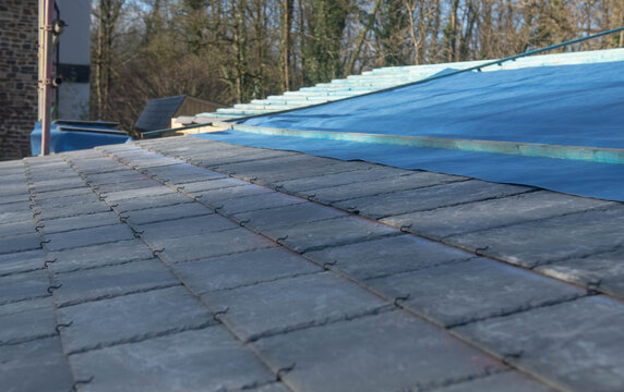 Replacing The Slate Tiles On A Low Pitch Roof On A Building In Rural Devon, England, UK