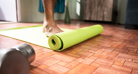 Young man at home arranging yoga mat before starting exercise - Concept of medical, helathcare,...