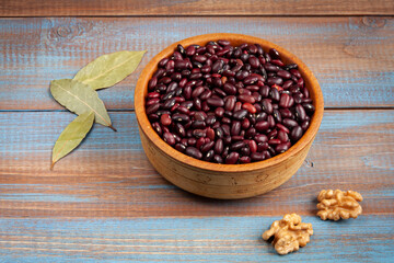 haricot beans in a wooden bowl, walnuts and laurel leaves on blue and brown wood boards