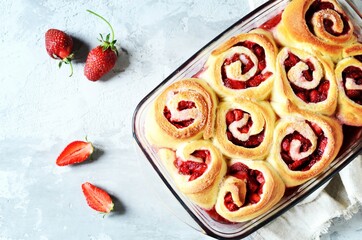Homemade yeast buns with strawberries on gray background