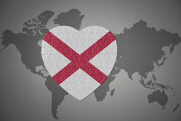 puzzle heart with flag of alabama state on a world map background.
