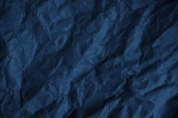 Black blue crumpled rough paper background. Wrinkled texture of colored packaging. Dark blue grunge background with copy space for design.