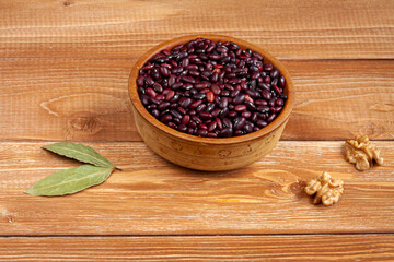 haricot beans in a wooden bowl, walnuts and laurel leaves on brown wood boards
