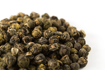 A pile of green jasmine pearl dried tea on a white background. Chinese traditional fragrant tea,...
