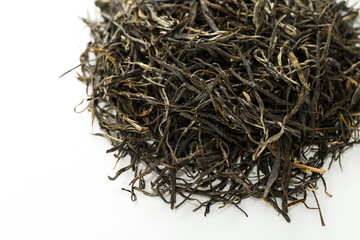 A heap of rolled needle green tea leaves on a white background. Traditional oxidized Chinese tea