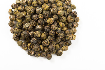 A handful of dried jasmine tea, taken close-up on a white background. Chinese jasmine pearl tea.