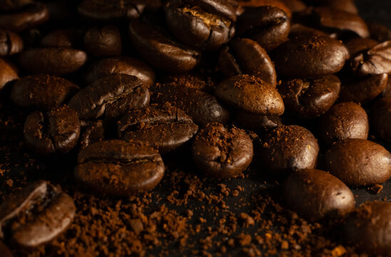 Mountain of coffee beans on black background with ground coffee and brown color © Julia