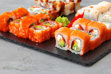 Set of various sushi rolls served on gray background