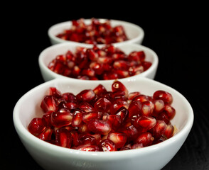juicy red pomegranate seeds in white bowls