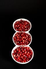 juicy red pomegranate seeds in white bowls