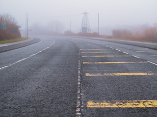 Fototapeta premium Empty asphalt road in town in a fog. Mist over town traffic. Dangerous conditions. Selective focus