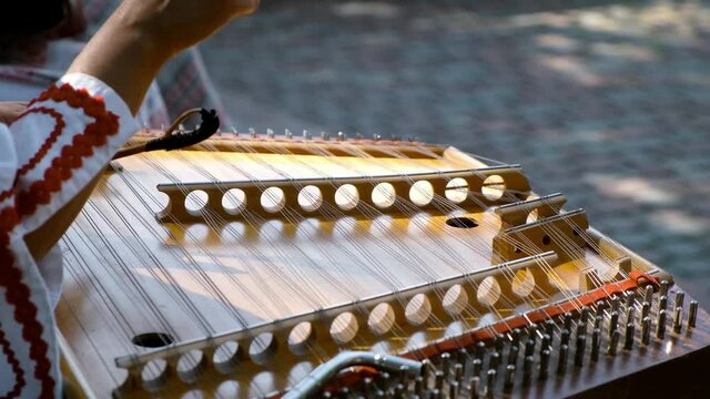 A close-up of an old, stringed musical instrument played by a woman.