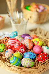 Fototapeta na wymiar Group of easter eggs painted with handmade and bright color in basket and paintbrush tools blur in the background