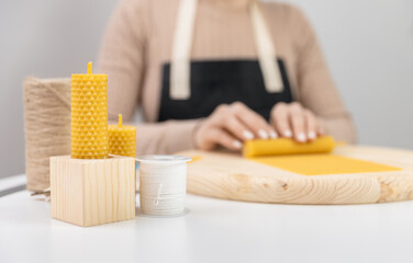 Craft production home, master rolls beeswax candles on white table