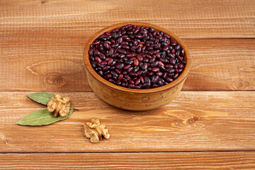 haricot beans in a wooden bowl, walnuts and laurel leaves on brown wood boards
