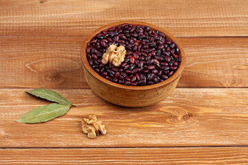 haricot beans in a wooden bowl, walnuts and laurel leaves on brown wood boards