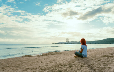 Woman on the beach at Baltic Sea. Red hair woman sitting on a beach.
