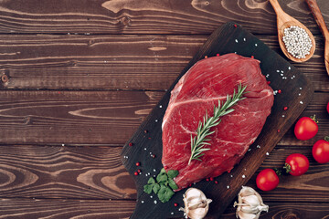 Raw beef steak with rosemary and spices on wooden board